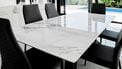 Een foto van een witte marmeren tafel met zwarte stoelen