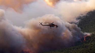 A firefighting helicopter flies as smoke rises from a wildfire in the area of Porto Germeno, some 70 kilometres (45 miles) northwest of Athens in the region of Viotia, on August 1, 2026. Hundreds of firefighters in Greece battle to save a popular coastal resort northwest of Athens as violent winds continued to lash the country, hampering operations. Hit hard by the climate crisis like the rest of the Mediterranean region, the country is plagued by wildfires every summer due to high temperatures, frequent heat waves, and drought.

Angelos TZORTZINIS / AFP