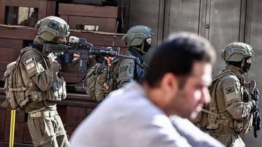 Israeli soldiers walk past a man during a military operation in the town of Qalqiya, in the occupied West Bank on December 4, 2025. 
Zain JAAFAR / AFP