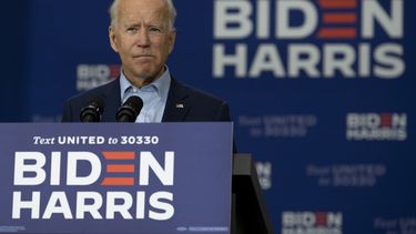 Op deze foto is presidentskandidaat Joe Biden te zien. Hij staat achter een bordje met 'Biden Harris'.