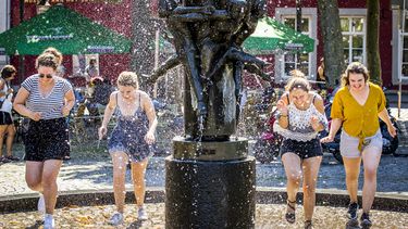 Een foto van vier meiden die verkoeling zoeken bij een fontein in Maastricht