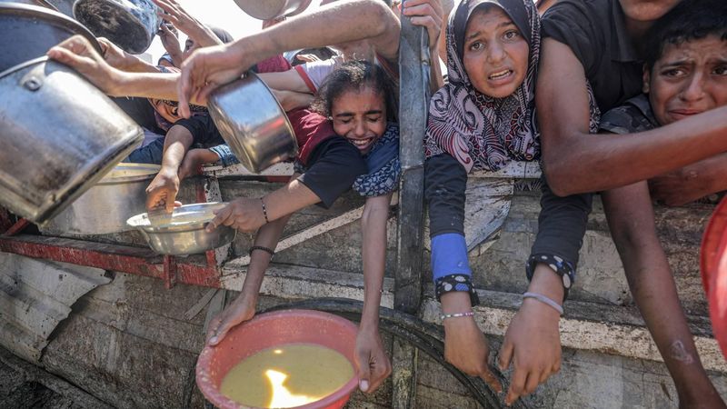 epa12282784 Internally displaced Palestinians, including children, hold pots as they receive food from a charity kitchen, in Gaza City, Gaza Strip, 04 August 2025. Humanitarian organizations have warned of an imminent food catastrophe for thousands of children, a crisis caused by severe food insecurity, a decline in health services, and ongoing restrictions on humanitarian aid and essential supplies.  EPA/MOHAMMED SABER