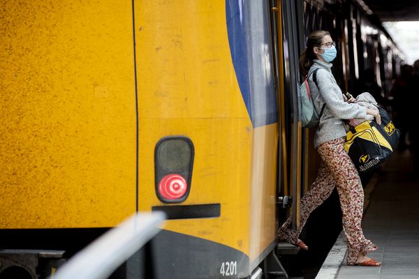 Een foto van een meisje met een mondkapje dat uit de trein stapt