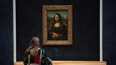 Een foto van een meisje dat naar de Mona Lisa in het Louvre kijkt