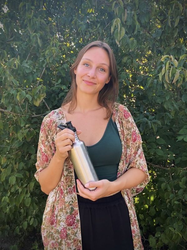 Een foto van Kiki Schollaardt met hergebruik-fles in de serie over zwerfafval