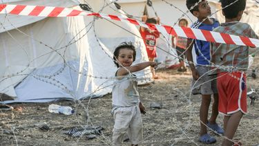 Op deze foto zijn drie kinderen in een vluchtelingenkamp te zien.
