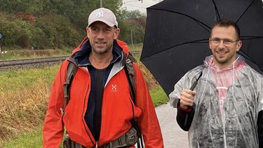 Op deze foto zijn de twee horecaondernemers te zien, ze wandelen door de regen.