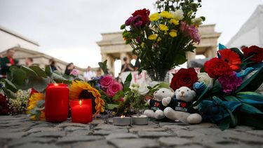 Bouquets of flowers, candles and Berlin bears are placed on July 26, 2026 in front of landmark Brandenburg Gate during to a so-called 