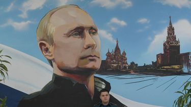 A serviceman of Russia's Emergencies Ministry sits under a mural depicting Russian President Vladimir Putin during Russia's parliamentary election at a polling station in Donetsk, Russian-controlled Ukraine, on September 20, 2026, amid the ongoing Russian-Ukrainian conflict. 
STRINGER / AFP