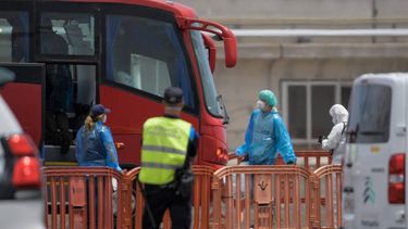 A passenger wearing a blue protective suit is guided to board military buses after being transferred from the Dutch flagged hantavirus-stricken cruise ship MV Hondius at the industrial port of Granadilla de Abona on the island of Tenerife in Spain's Canary Islands on May 10, 2026 Repatriation flights for the nearly 150 passengers onboard the ship hit by a deadly hantavirus outbreak began as passengers were transferred to shore on smaller vessels then by bus to the airport to be flown home after weeks at sea.

JORGE GUERRERO / AFP