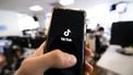 This photograph taken on April 19, 2024 shows a man holding a smartphone displaying the logo of Chinese social media platform Tiktok in an office in Paris 
Antonin UTZ / AFP