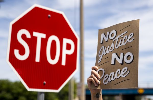 Op deze foto is een bord te zien met 'no justice, no peace' erop.