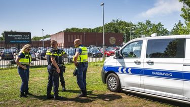 TER APEL - Politie en Handhaving controleren een asielzoeker die een biertje op ht veld bij het aanmeldcentrum in Ter Apel drinkt. Het Rode Kruis en VluchtelingenWerk zijn gestopt met hulpverlening, omdat het volgens hen niet langer veilig was voor hulpverleners en hulpvragers. JILMER POSTMA / ANP