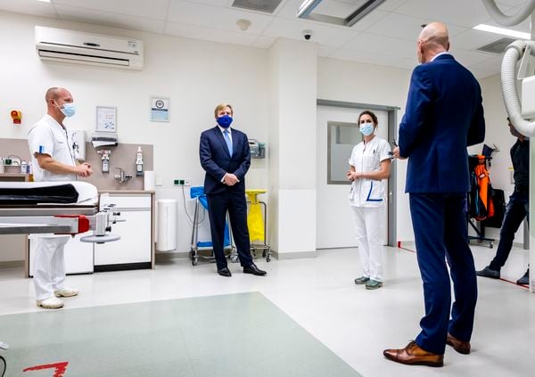 Een foto van de koning die aandachtig luistert naar ziekenhuispersoneel en Ernst Kuipers