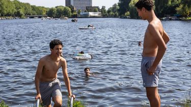 AMSTERDAM - Zonaanbidders koelen af bij het water in de binnenstad van Amsterdam. Vanwege het warme weer is het Nationaal Hitteplan in het hele land van kracht. DINGENA MOL / ANP