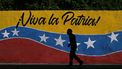 A man walks past a mural depicting the Venezuelan national flag and reading 