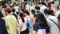 Een foto van een drukke straat in Hong Kong, iedereen draagt een mondkapje