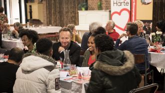 Op deze foto is Joris Linssen te zien, hij zit met een groepje mensen aan tafel in een restaurant van Resto VanHarte