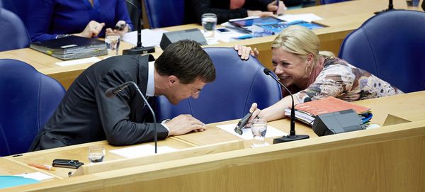 Premier Mark Rutte bekijkt de telefoon van minister Jeanine Hennis-Plasschaert van Defensie tijdens de Algemene Politieke Beschouwingen in de Tweede Kamer. Foto: ANP / Martijn Beekman