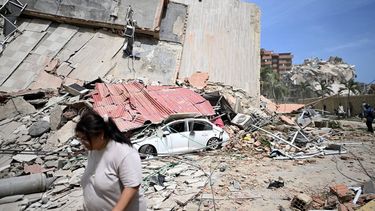 A woman walks past a car crushed under the collapsed remains of a corrugated metal roof amid debris following an earthquake in Catia La Mar, La Guaira state, about 30 km northwest of Caracas, on June 25, 2026. A twin earthquake that was Venezuela's largest in over a century has killed at least 164 people and destroyed multiple buildings near the capital, where residents searched on June 25 for missing relatives.
Juan BARRETO / AFP