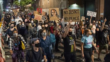 Op deze foto zijn demonstranten te zien die borden vasthouden met daarop 'no justice, no peace' en foto's van Breonna Taylor erop.