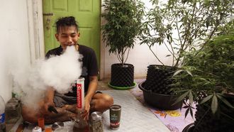 Thaise man rookt wiet naast zijn eigen wietplanten