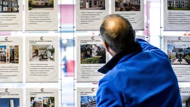 HAARLEM - Een man kijkt naar advertenties van huizen die te koop staan bij een makelaar in Haarlem. De huizenprijzen gaan niet alleen volgend jaar, maar waarschijnlijk ook het jaar daarna duidelijk omlaag. De Nederlandsche Bank (DNB) verwacht in een nieuw rapport dat woningen in twee jaar meer dan 6 procent minder waard zullen worden, ondanks dat het leven over de gehele linie wel duurder wordt ANP REMKO DE WAAL