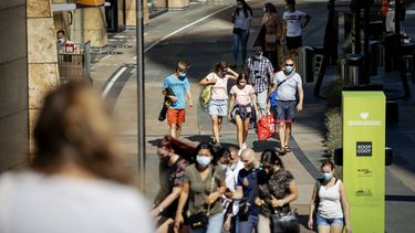 Op deze foto zijn mensen in het centrum van Rotterdam te zien. Ze dragen een mondkapje.
