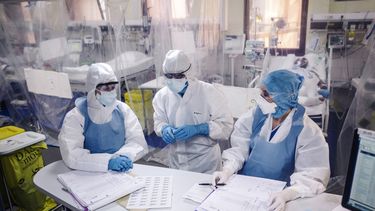 Op deze foto zijn drie artsen in het ziekenhuis te zien. Ze dragen beschermde kleding.