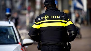 GRONINGEN - Een politieagent in een operationeel uniform op straat naast een politieauto. Politie, surveilleren, patrouille. ANP XTRA KOEN VAN WEEL