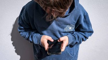 This photo taken on October 24, 2025 shows a 14-year-old boy posing at his home near Gosford as he looks at social media on his mobile phone.  Tech giants Meta and TikTok said on October 28 they will obey Australia's under-16 social media ban but warned the landmark laws could prove difficult to enforce. Australia will from December 10 force social media platforms such as Facebook, Instagram and TikTok to remove users under the age of 16. 
David GRAY / AFP
