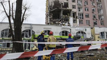 Ukrainian rescuers stand in front of a damaged residential building following Russian drones and missiles attack in Kyiv, on December 27, 2025, amid the Russian invasion in Ukraine. Russia pummelled Ukraine's capital with drones and missiles on December 27, killing a woman and cutting power to hundreds of thousands, ahead of the latest talks between the presidents of Ukraine and the US.

VLADYSLAV MUSIENKO / AFP