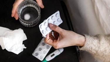 ILLUSTRATIEF - Een vrouw pakt paracetamol vanuit bed. Het aantal mensen dat zich bij de huisarts meldt met griepachtige klachten neemt verder toe. ANP REMKO DE WAAL
