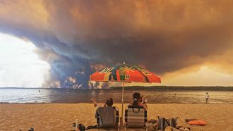 Beachgoers sit on the beach of Moutchic in Lacanau, southwestern France on July 24, 2026, as clouds of smoke rise into the sky from a wildfire. The fire raging in the northern part of the Arcachon Basin in Gironde, southwest France, has swept through more than 3,400 hectares, according to the latest figures released by the prefecture. More than 20,000 residents and tourists have been evacuated from this part already devastated by flames in 2022. Scientists have long warned that climate change caused by human use of fossil fuels will make periods of drought more intense and longer-lasting, creating the ideal conditions for wildfires.
Maximilien LAMY / AFP