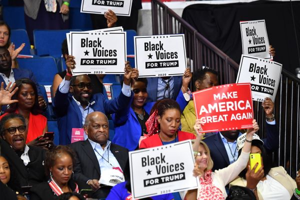 Een foto van publiek met bordjes met de tekst Black Voices for Trump