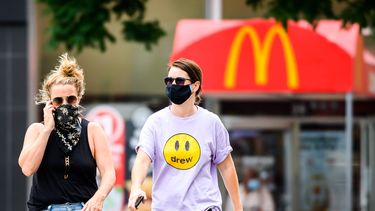 Een foto van twee dames met een mondkapje voor een McDonald's-vestiging