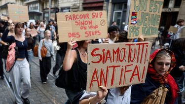A high school student holds a sign reading