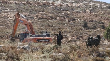 Israeli forces guard a bulldozer reportedly operating on Palestinian lands as local Palestinian landowners (unseen) gather in protest against land confiscations near the village of Dura, west of Hebron in the Israeli-occupied West Bank, on June 9, 2026. 
HAZEM BADER / AFP