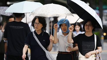 People shelter from the heat under umbrellas in Seoul on August 4, 2026. South Korea's summer heat has killed 16 people so far this year, the interior ministry said August 4, as the nation swelters in a wave of searing weather.

GREG BAKER / AFP