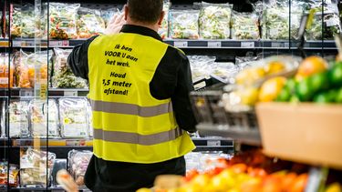 Een foto van een medewerker van een supermarkt in een geel hesje