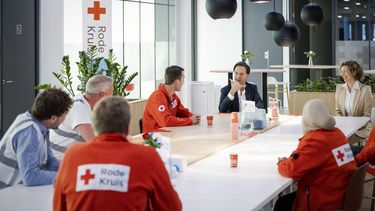 Op deze foto is Mark Rutte te zien, in gesprek met medewerkers van het Rode Kruis.