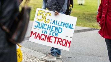 Een foto van iemand bij een 5G demonstratie met een bord waarop staat: 5G: allemaal juichend in een magnetron