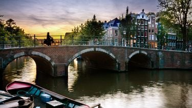 Een vrouw fiets over een brug in Amsterdam