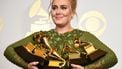 Een foto waarop zangeres Adele te zien is met muziekprijzen in haar armen.