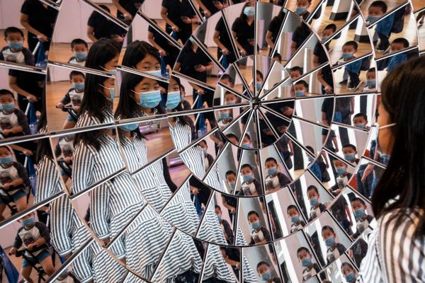 Een foto van het Sciene Museum in Londen waarbij een meisje met een mondkapje zichzelf in talloze spiegels ziet