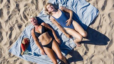 Een foto van twee zonnende dames op het strand van Scheveningen