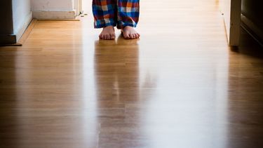 Een jongen in pyjama met knuffelbeer staat in de deuropening.
