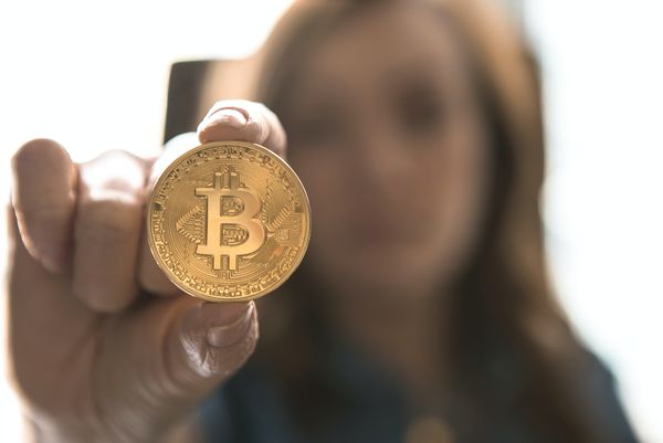 Een foto van een vrouw met een Bitcoin tussen de vingers