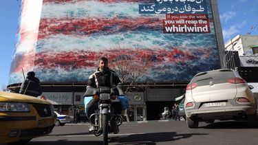 epa12693998 Iranians drive near a huge anti-US billboard hanging at the Enqelab square in Tehran, Iran, 31 January 2026. The US President Donald Trump renewed threats of military action against Iran following anti-government protests. Iran is experiencing a nationwide internet blackout that began on 08 January 2026, amid an intensifying wave of anti-government protests.  EPA/ABEDIN TAHERKENAREH