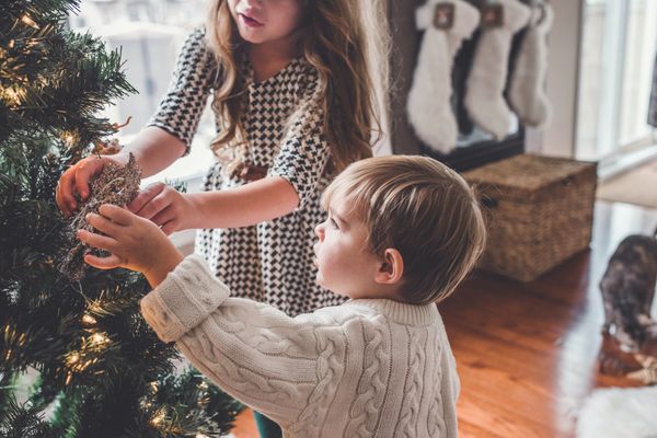 Op deze foto versieren twee kinderen een kerstboom.